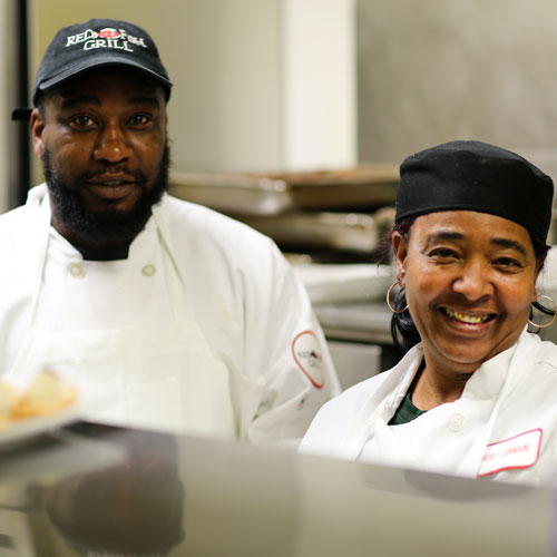 Two kitchen employees smiling for the camera